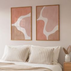 two paintings hang on the wall above a bed