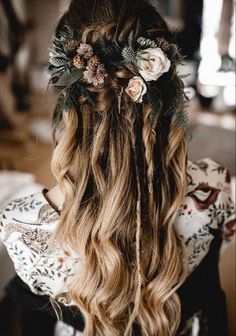 a woman with long blonde hair and flowers in her hair is shown from the back