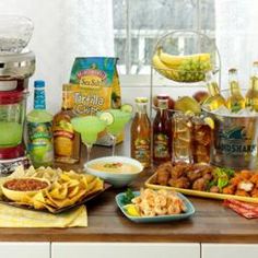 there are many different foods on the table together in this kitchen, including salads and condiments