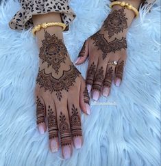 two hands with henna tattoos on them, one is wearing gold bracelets and the other has leopard print