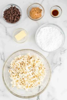 ingredients to make chocolate chip cookies laid out in bowls on a marble counter top,