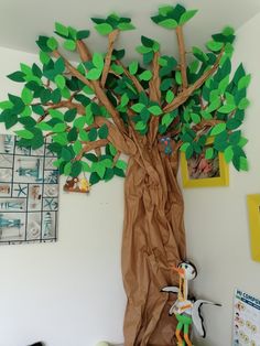 a tree made out of brown paper with green leaves and a stuffed animal in the middle