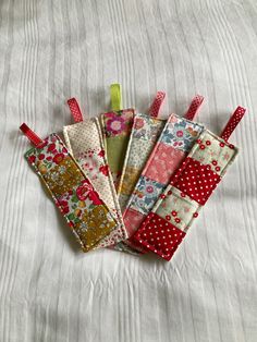 four pieces of fabric sitting on top of a white bed covered in polka dots and flowers