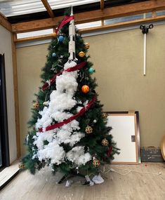 a white christmas tree with red ribbon around it