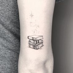 a woman's arm with a tattoo that has books on it and stars above the book