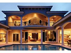 a large house with a swimming pool in front of it at night, lit up by lights