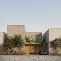 a car parked in front of a concrete building with trees and bushes on the side