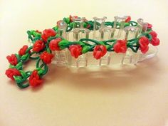 a plastic bracelet with red flowers and green leaves on it, sitting on a table