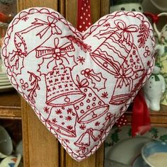 a red and white heart hanging from a wooden door with dishes on the shelves behind it