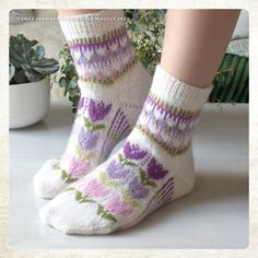 a woman's legs wearing socks with purple flowers on them and green plants in the background