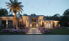 a house that is lit up at night with flowers in the front yard and palm trees