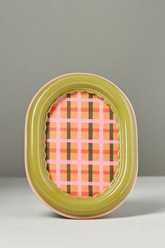 a green frame with an orange and pink checkered pattern on the front, sitting on a white surface