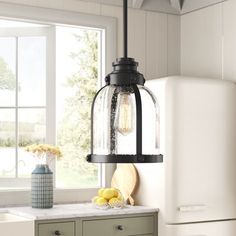 a kitchen light hanging over a counter top next to a refrigerator freezer and window