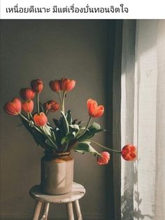 there is a vase with flowers in it sitting on a stool next to the window