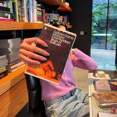 a person sitting in a chair holding up a book