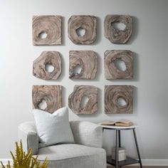 a living room with white furniture and wood pieces on the wall