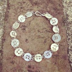 a close up of a metal bracelet on a stone surface with two charms attached to it