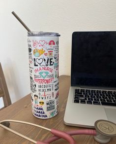 a laptop computer sitting on top of a wooden table next to a cup filled with coffee