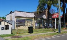 an old building with graffiti on the side of it next to a fence and palm trees