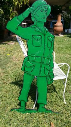 a cardboard cut out of a man in green uniform standing on the grass next to a lawn chair