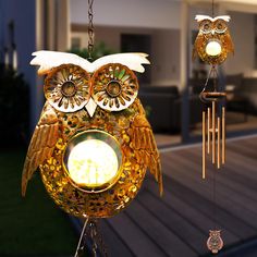 an owl wind chime hanging from a chain with two lights on it's face