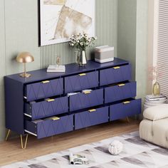 a blue dresser with gold handles and drawers in a living room next to a couch