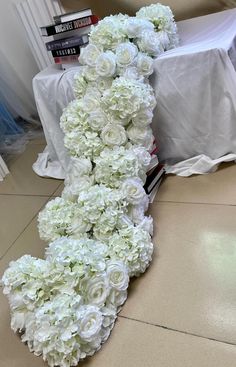 a bunch of white flowers on the floor next to a table with a bookcase