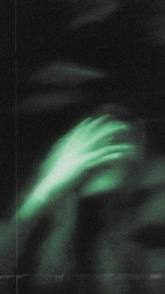 blurry photograph of an object in the dark with green light coming from behind it