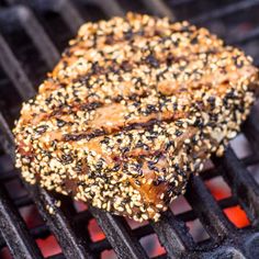 some kind of food is cooking on a bbq with sesame seeds and other toppings