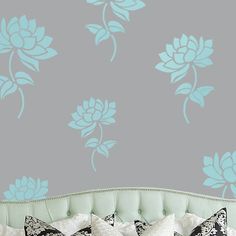 a bed sitting under a blue flower wall decal on top of a gray wall