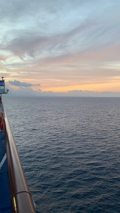 the back end of a cruise ship as it sails out to sea at sunset or dawn