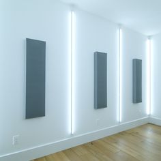 a white room with three black rectangular pieces on the wall and one is lit up