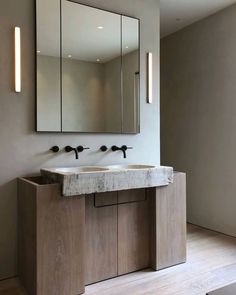 a bathroom sink sitting under a large mirror next to a wall mounted faucet