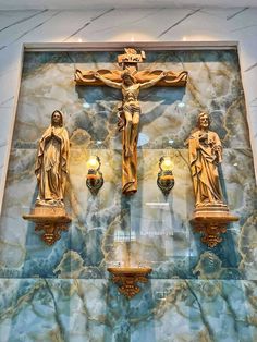 three golden crucifixs are on display in front of a marble wall