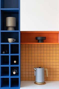 an orange and blue shelf next to a coffee pot