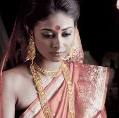 a woman in an orange and white sari with gold jewelry on her neck, wearing a necklace