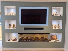 a television mounted on the wall above a fire place with many shelves filled with figurines