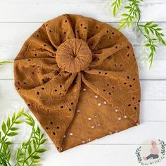 a brown headband with white dots and a large bow on the side, sitting next to some green leaves