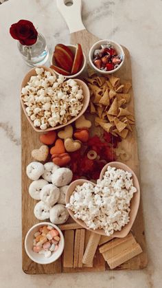 a wooden cutting board topped with bowls filled with different types of snacks and toppings