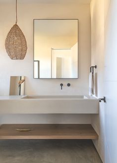 a bathroom with a sink, mirror and hanging light fixture in the middle of it