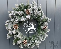 a christmas wreath hanging on the side of a building with pine cones and evergreens