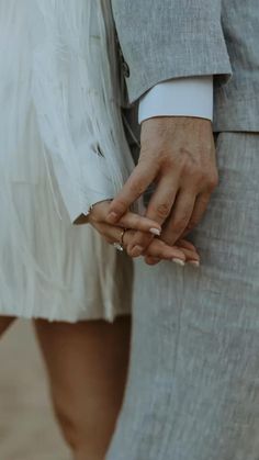 the bride and groom hold hands as they stand close to each other with their wedding rings on their fingers