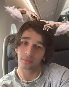 a man sitting on an airplane with his hair in the air and hands above his head