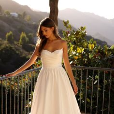 a woman in a white dress standing on a balcony