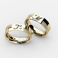 two gold wedding rings with initials on each side and the word love written in black lettering