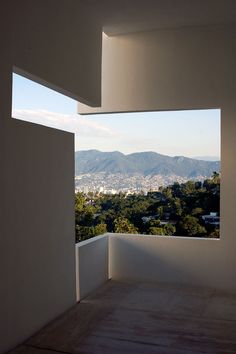 an open window looking out at the mountains and trees in the distance from a balcony