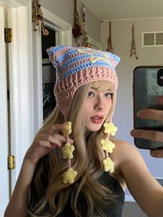 a woman taking a selfie with her cell phone wearing a crocheted hat