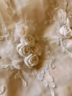 white fabric with flowers and lace on the bottom, as well as an applique