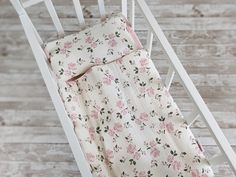 a white rocking chair with a pink flowered blanket on top of it and a wooden floor in the background