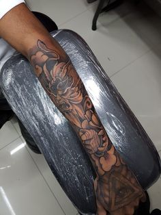 a man with a tattoo on his arm sitting in a barbershop holding a hair dryer